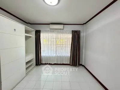 Spacious bedroom with large window and built-in wardrobe, perfect for natural light lovers.