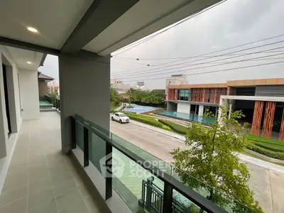 Modern balcony with glass railing overlooking pool and contemporary architecture.