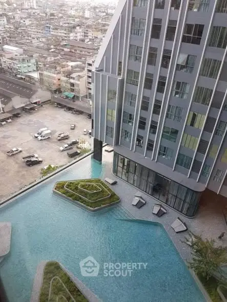 Stunning aerial view of modern high-rise building with luxurious pool and cityscape backdrop.