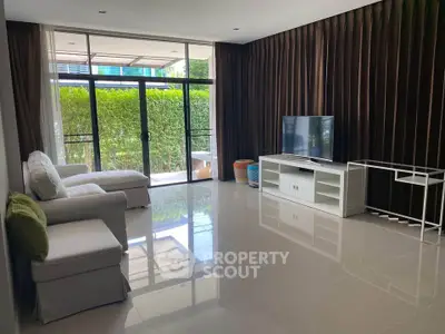 Spacious living room with modern decor and large windows overlooking greenery.
