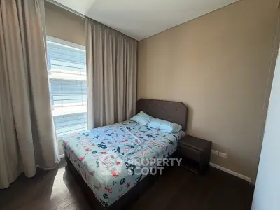 Cozy bedroom with modern decor and ample natural light from large window.