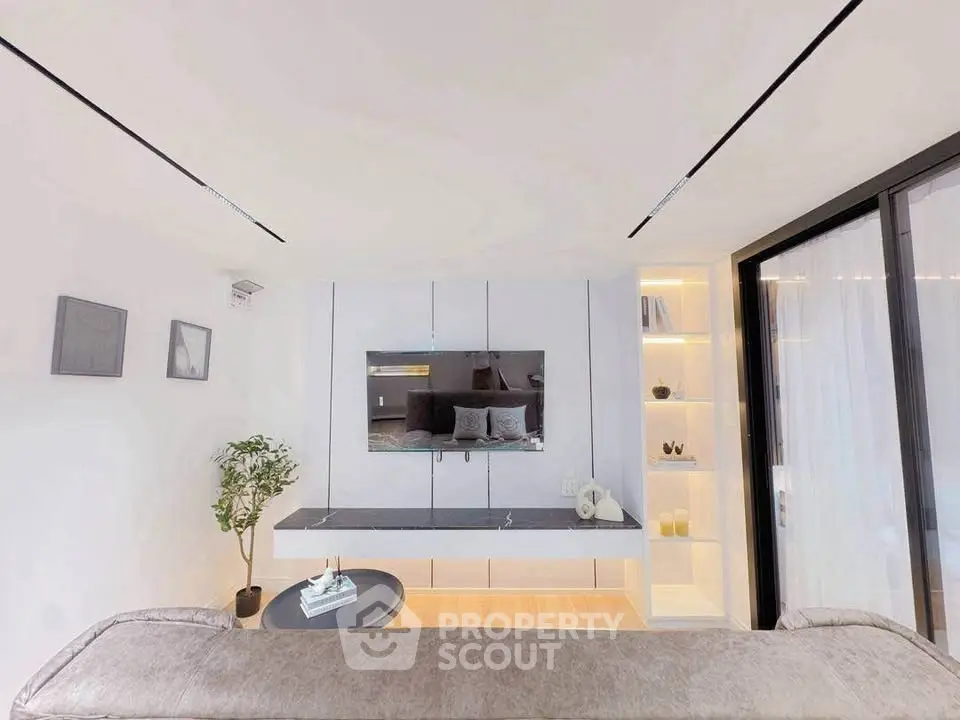 Modern living room with sleek design, featuring a wall-mounted TV, stylish shelving, and cozy seating area.