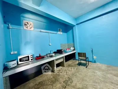 Minimalist kitchen with blue walls, concrete floor, and basic appliances.