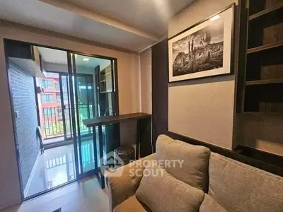 Cozy living room with sliding glass doors leading to a balcony, featuring modern decor and comfortable seating.