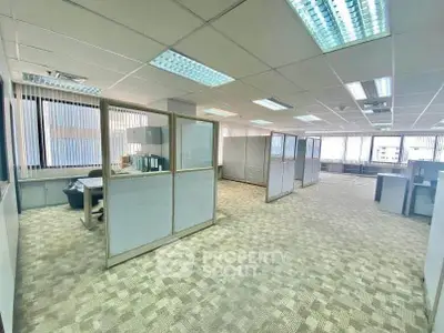 Spacious office space with cubicles and large windows for natural light.