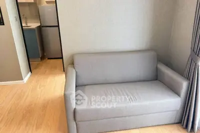 Modern apartment interior with cozy gray sofa and compact kitchen area.