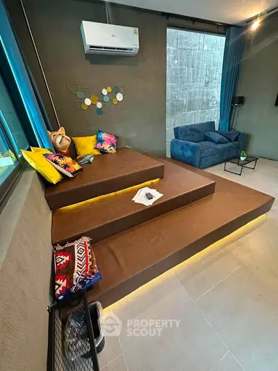Modern living room with stylish seating, vibrant cushions, and sleek air conditioning unit.