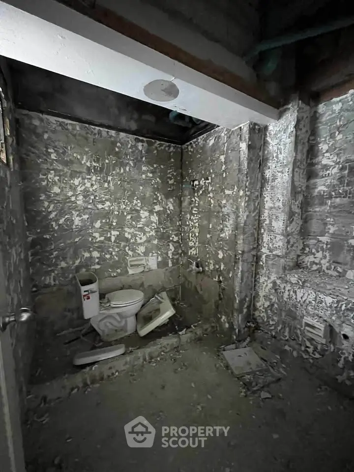 Unfinished bathroom with exposed concrete walls and toilet installation.