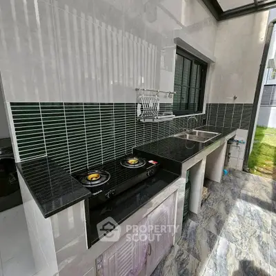 Modern outdoor kitchen with sleek black countertops and gas stove, perfect for entertaining.