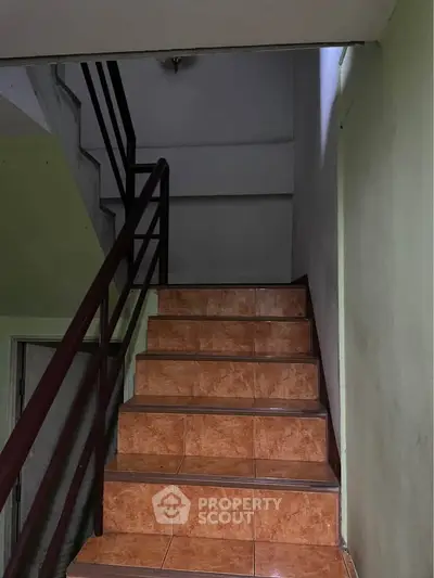 Staircase with tiled steps and metal railing in a residential building