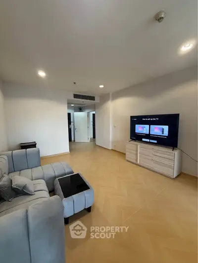 Spacious living room with modern decor and large TV, perfect for relaxation and entertainment.