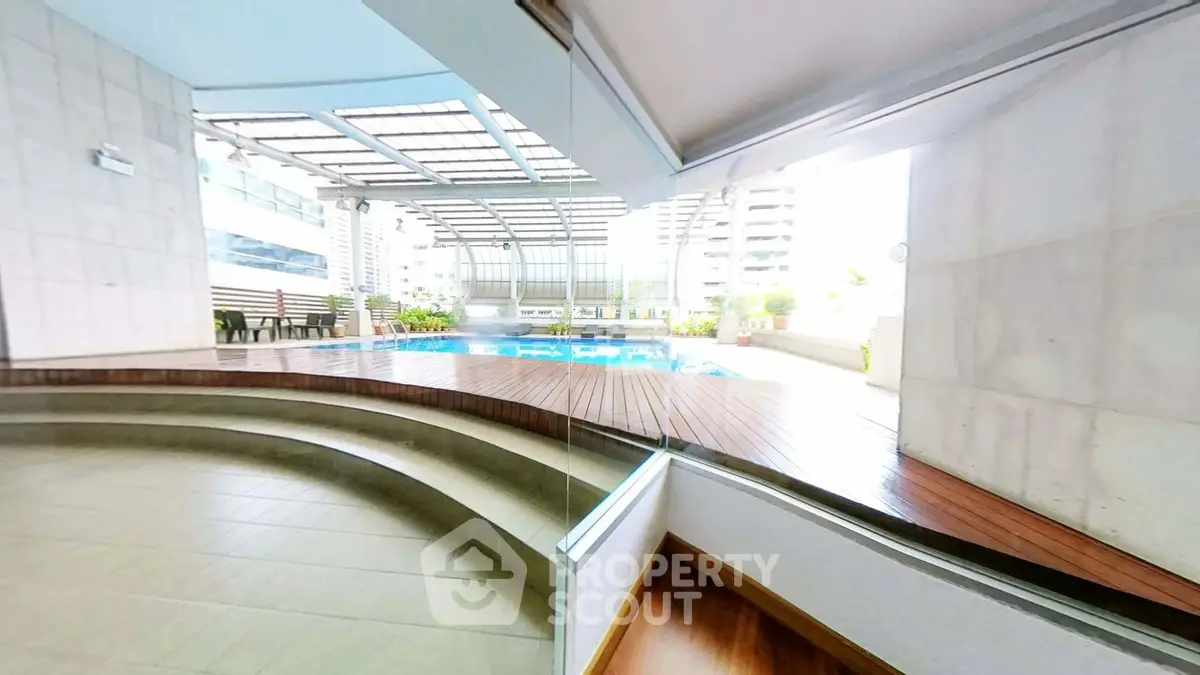 Luxurious apartment complex with modern pool and stylish outdoor seating area.
