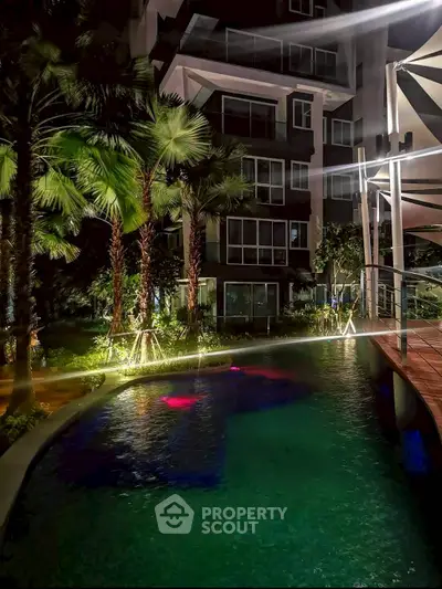 Luxurious night view of a modern apartment building with illuminated pool and lush greenery.
