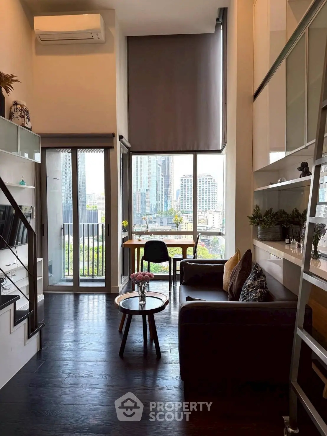 Modern loft-style living room with high ceilings and city view, featuring sleek furniture and large windows.