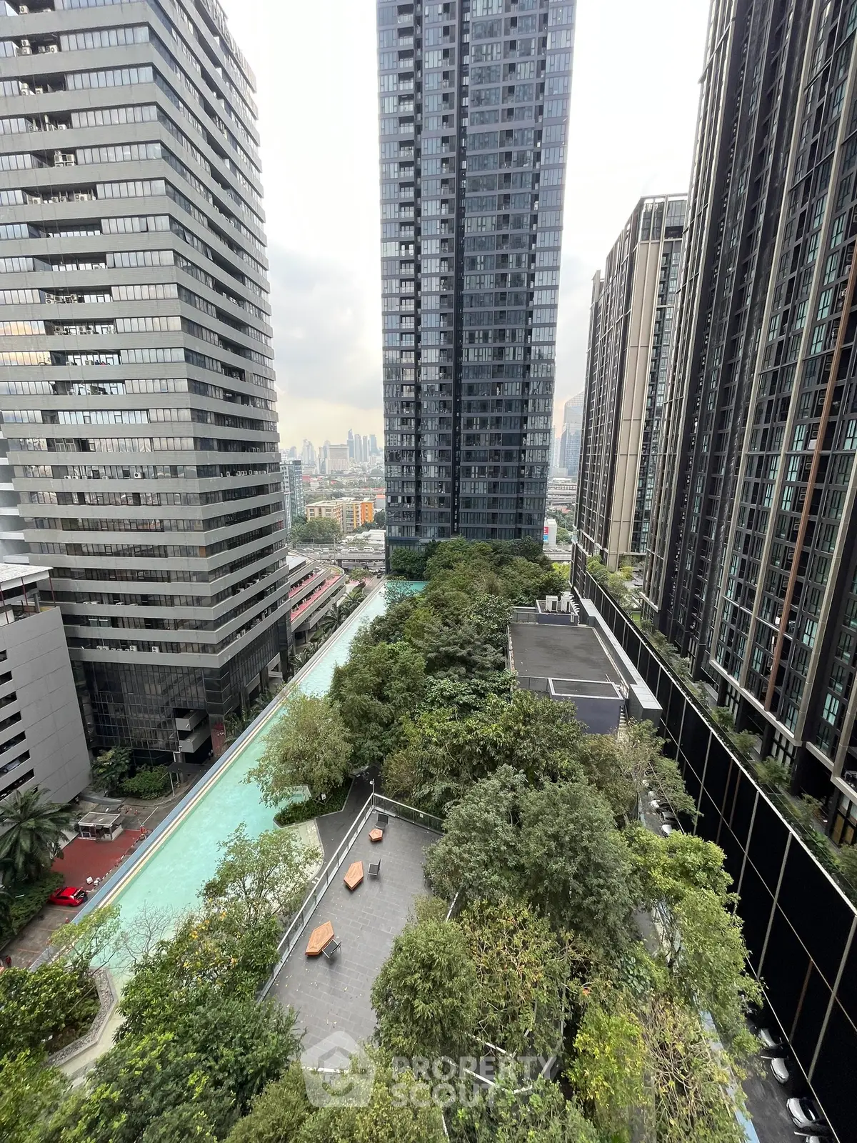Stunning urban high-rise view with lush greenery and a luxurious pool, perfect for modern city living.