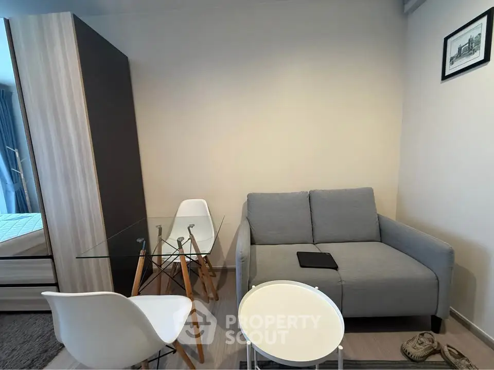 Modern living room with gray sofa, glass dining table, and minimalist decor