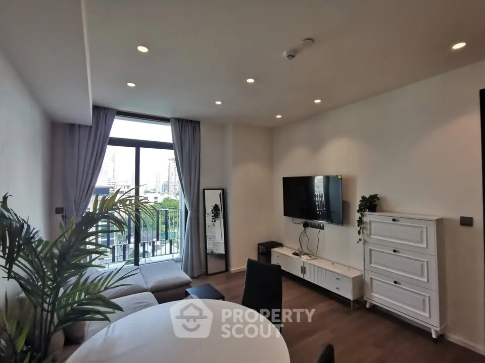 Modern living room with balcony view, stylish furniture, and natural light.