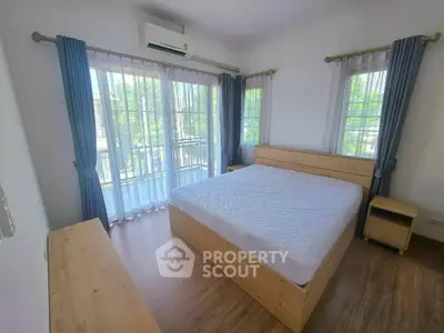 Bright and airy bedroom with large windows and wooden furniture, perfect for relaxation.