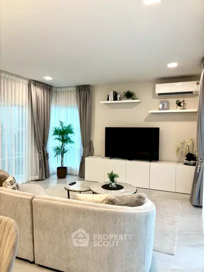 Elegant living room with modern decor, large TV, and cozy seating area.