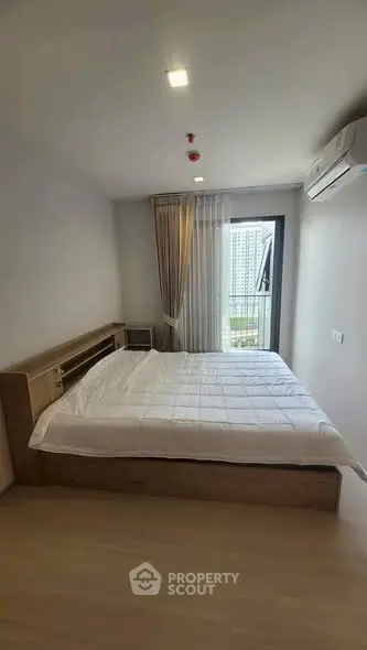 Modern bedroom with large window and city view, featuring a comfortable bed and air conditioning.