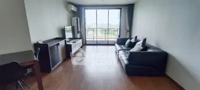Spacious living room with modern furniture and large window offering city view.