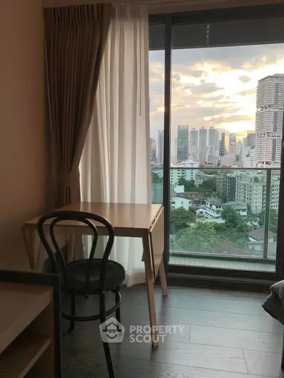 Charming city view from a cozy apartment with a small desk and chair by the window.