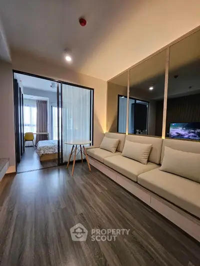 Modern living room with sleek design and cozy seating, leading to a stylish bedroom with natural light.