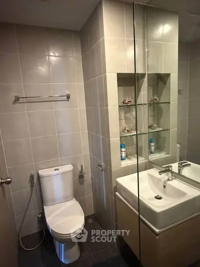 Modern bathroom with sleek fixtures and tiled walls, featuring a toilet and stylish sink area.