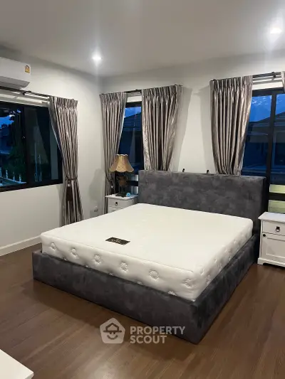 Spacious bedroom with elegant decor and large windows for natural light.