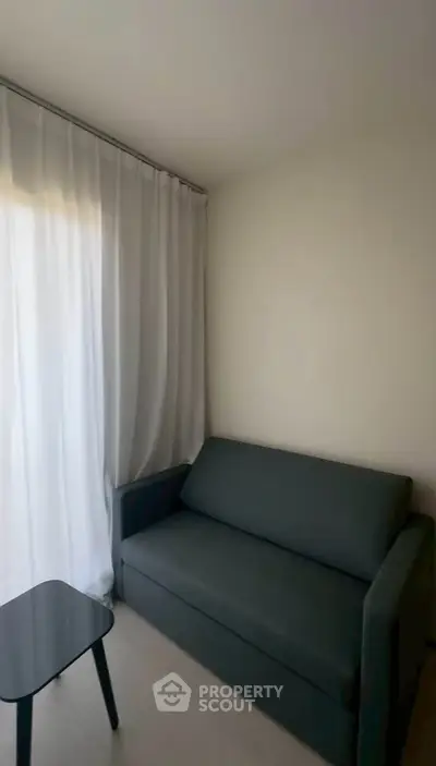 Cozy living room with modern sofa and sheer curtains, perfect for relaxation.