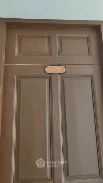 Elegant wooden apartment door with unit number, showcasing quality craftsmanship and secure entry.
