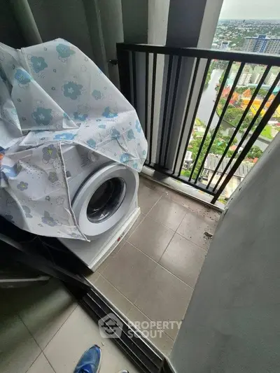 Compact balcony with washing machine and city view, ideal for urban living convenience.