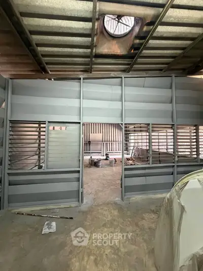 Industrial warehouse interior under renovation with metal walls and ceiling, showcasing spacious layout.