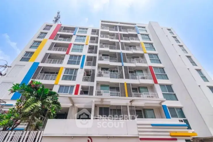 Modern multi-story building with colorful facade and balconies in urban setting.