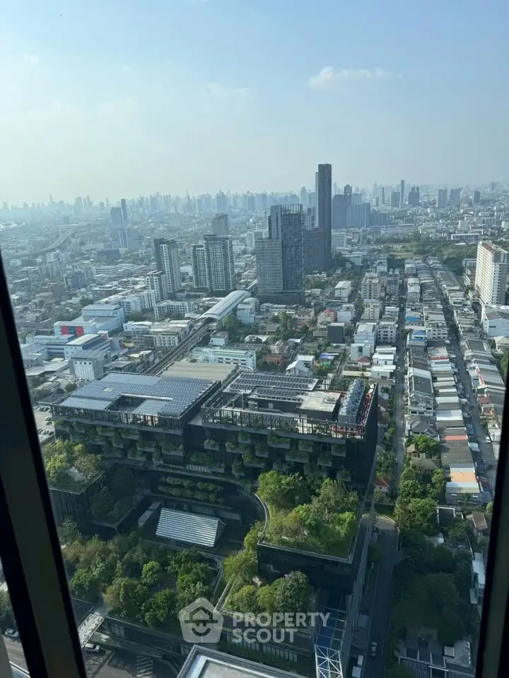 Stunning cityscape view from high-rise building showcasing urban skyline and lush green rooftops.