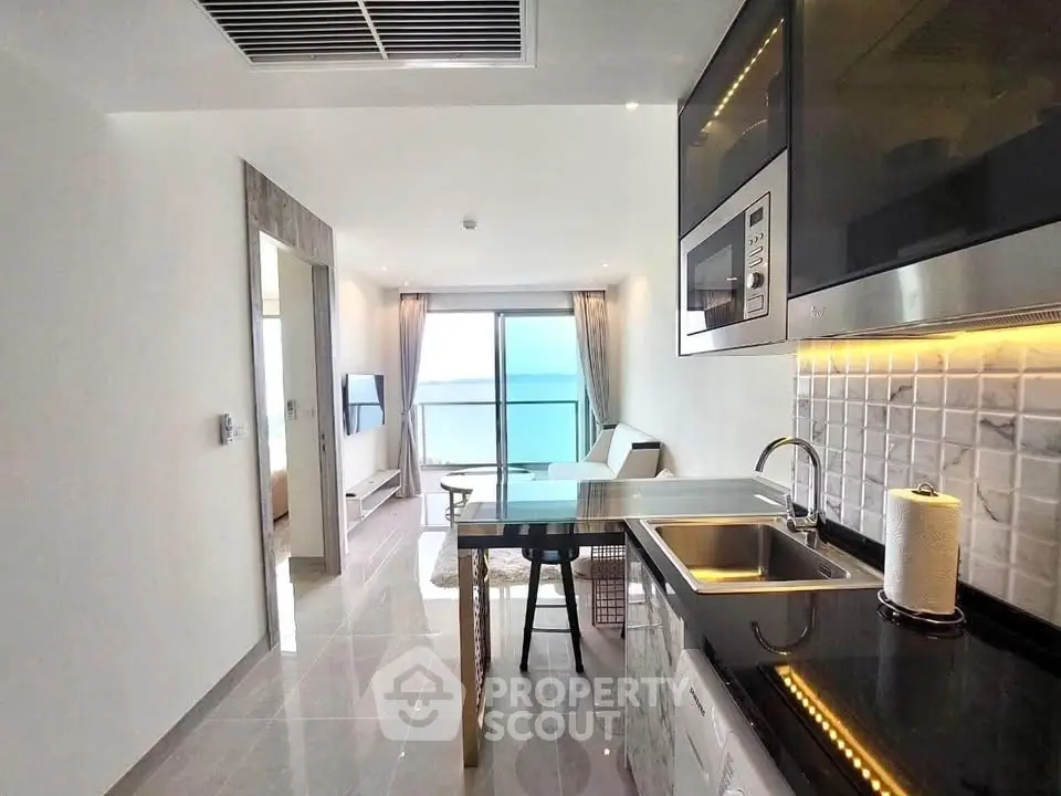 Modern open-layout kitchen with sleek appliances and ocean view balcony.