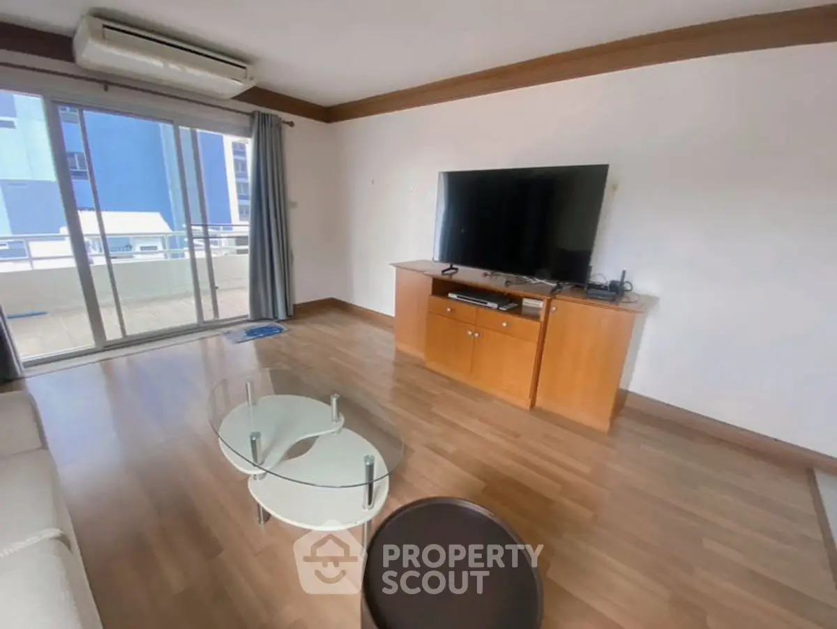 Spacious living room with modern TV setup and balcony access