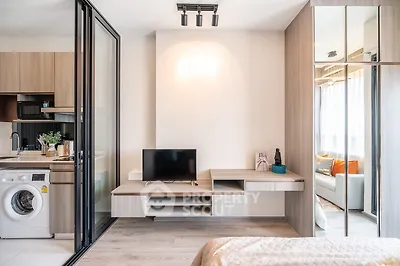 Modern studio apartment with open kitchen and cozy living area, featuring sleek design and natural light.