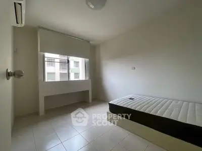 Minimalist bedroom with single bed and large window in modern apartment.