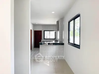 Modern kitchen with sleek white tiles and gas stove in a bright, minimalist design.