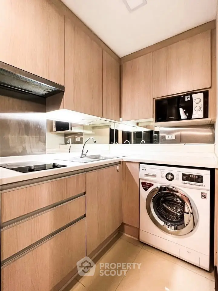 Modern kitchen with sleek cabinetry and integrated appliances, featuring a washing machine and microwave.
