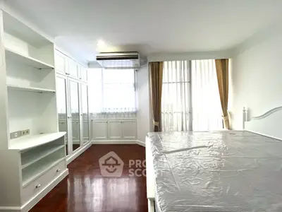 Spacious bedroom with elegant built-in storage and large windows for natural light.