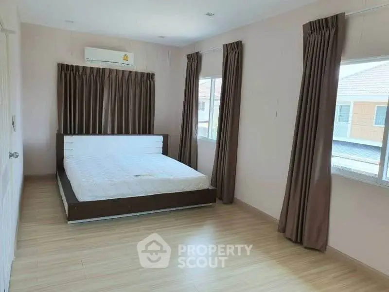 Spacious bedroom with large windows and modern decor in a bright, airy setting.