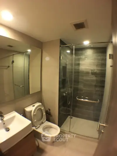 Modern bathroom with glass shower and sleek fixtures in contemporary apartment.