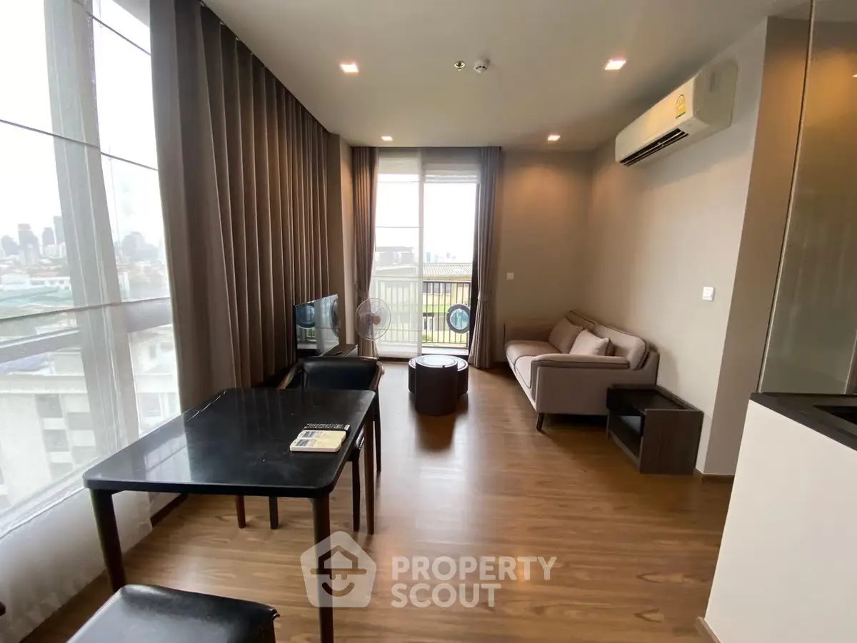Modern living room with city view, featuring sleek furniture and large windows for natural light.
