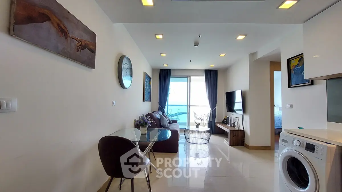 Modern living room with sea view, stylish furniture, and washing machine in open layout.