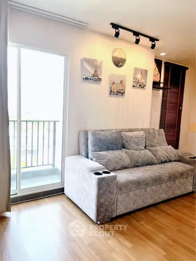 Stylish living room with cozy gray sofa and balcony access, perfect for relaxation and enjoying natural light.