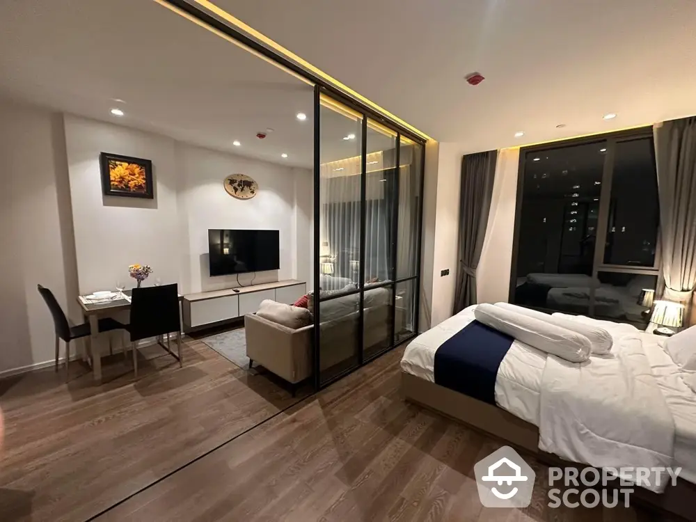 Modern studio apartment with glass partition, cozy living area, and elegant bedroom.