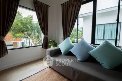 Cozy living room with large windows and modern sofa, offering a serene view of greenery.