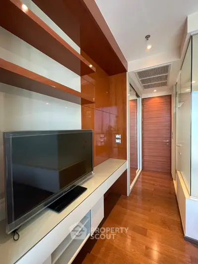 Modern living room with sleek wooden flooring and built-in TV unit